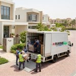 Classic Movers truck and moving crew carrying boxes during a villa relocation in Business Bay Dubai with Burj Khalifa in the background.