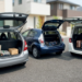 Three compact Japanese vehicles parked with their open boots displaying luggage and cargo space.